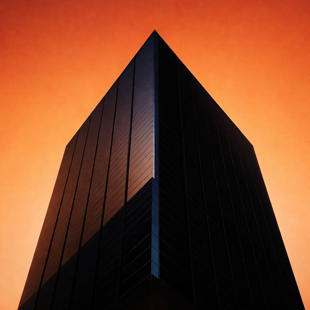 Torre corporativa escura recortada contra um céu alaranjado